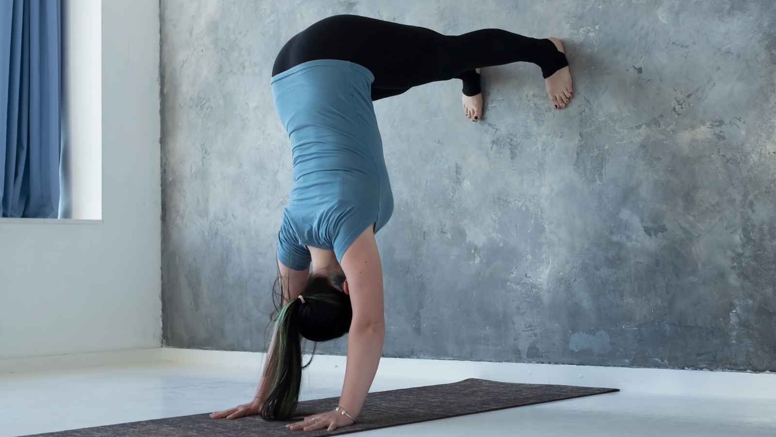 Woman learning to practice Handstand near the wall. Upside down yoga position.