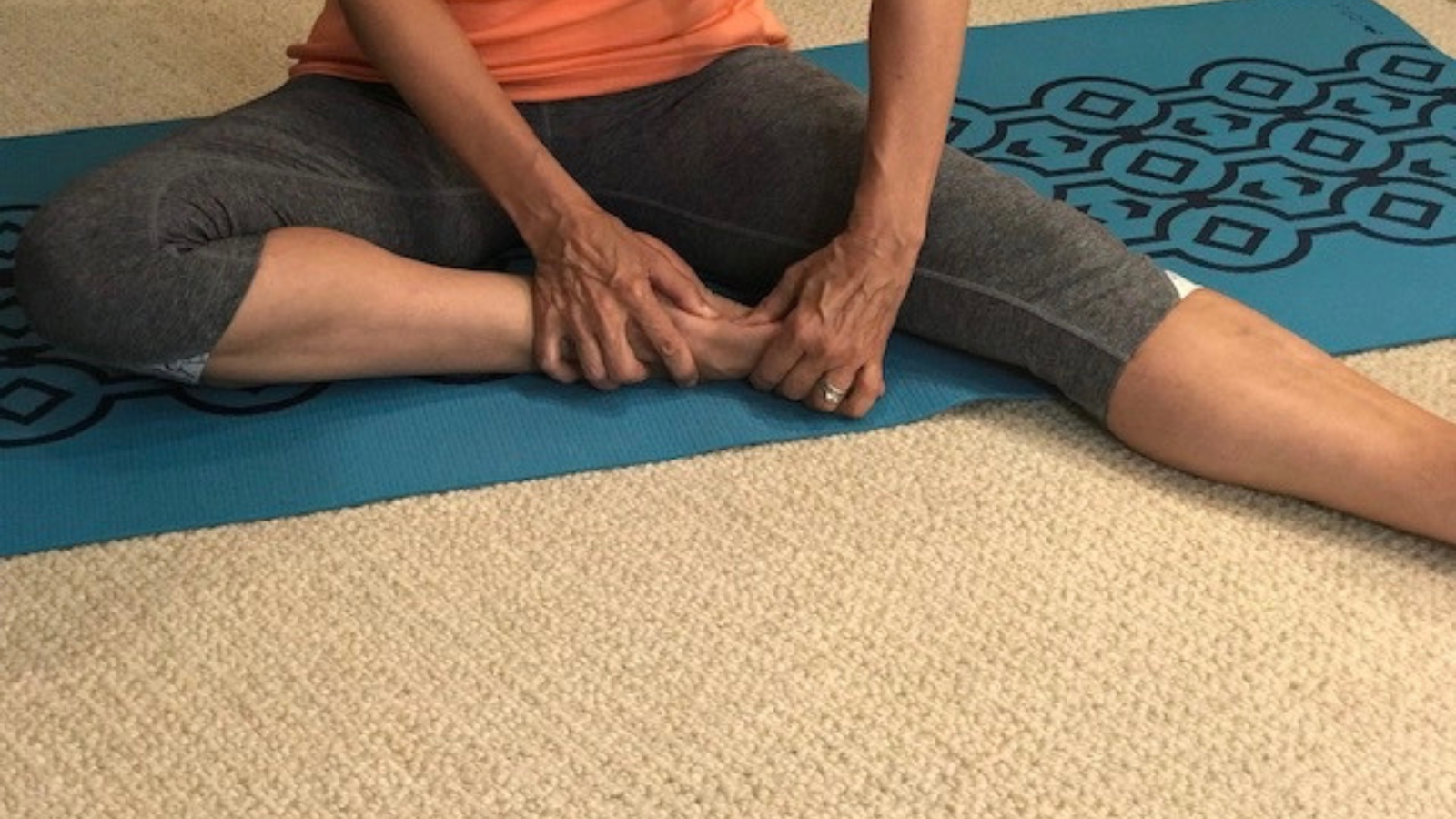 Image depicts yoga teacher using her thumbs to deep massage her feet.