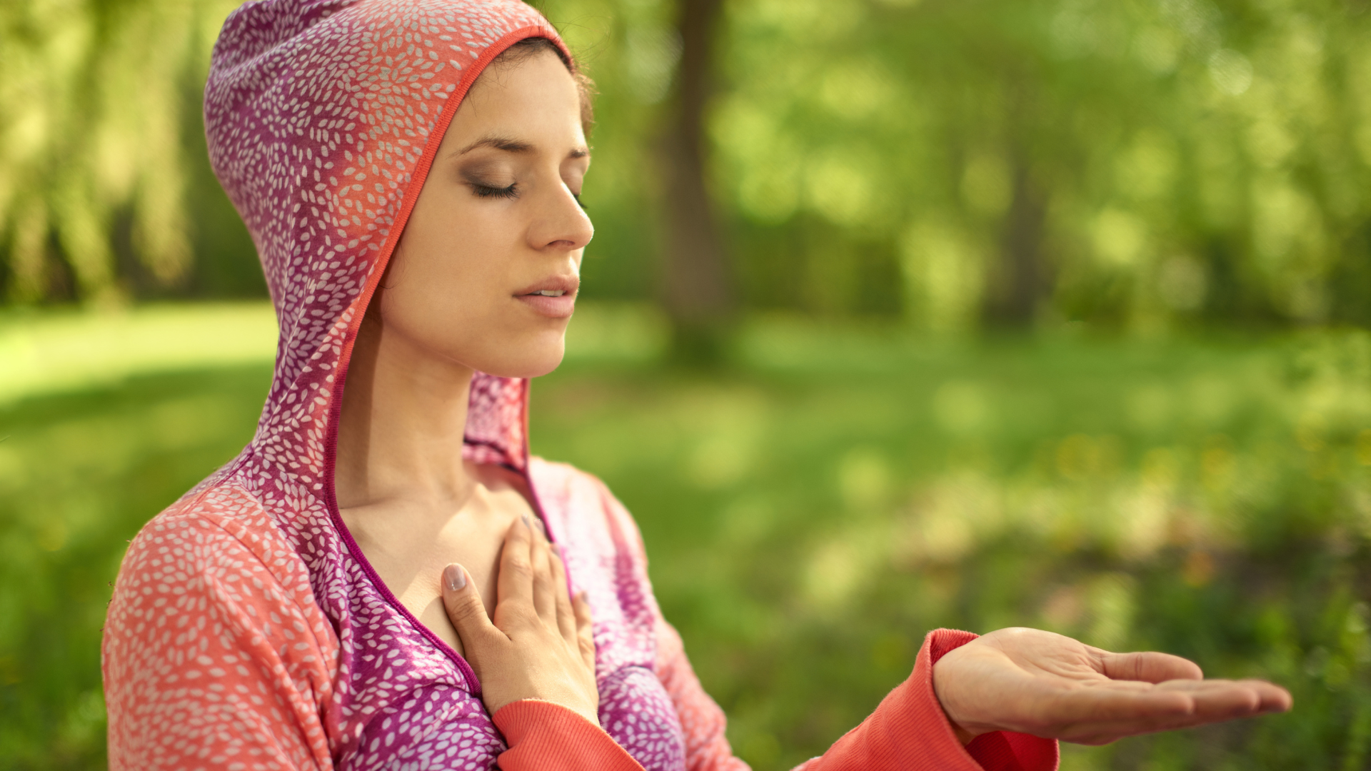 Portrait of beautiful mixed race, middle eastern girl meditating and doing yoga at sunset on the grass in a park or forrest. Concept of Self-Accomplishments and Gratitude.