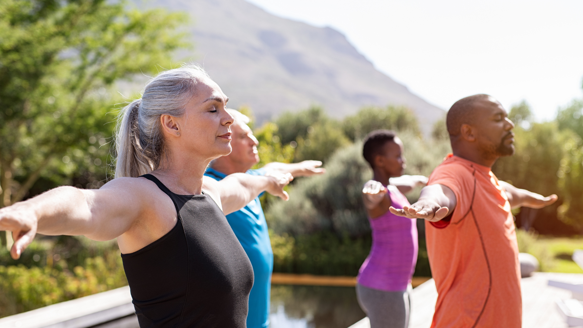 Group of senior yogis with closed eyes practicing yoga outdoors. Happy mature people doing breath practices and yoga class for greater health and well being and osteoporosis prevention.