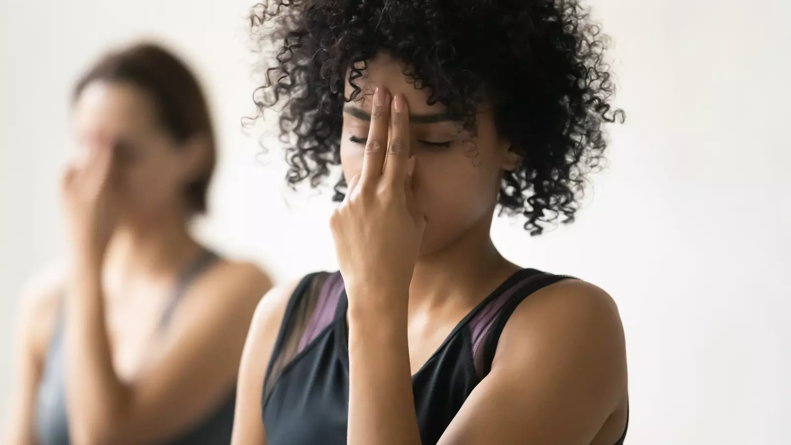 During yoga class women practicing Alternate Nostril a powerful mindful breathing practice energizing the third eye chakra.