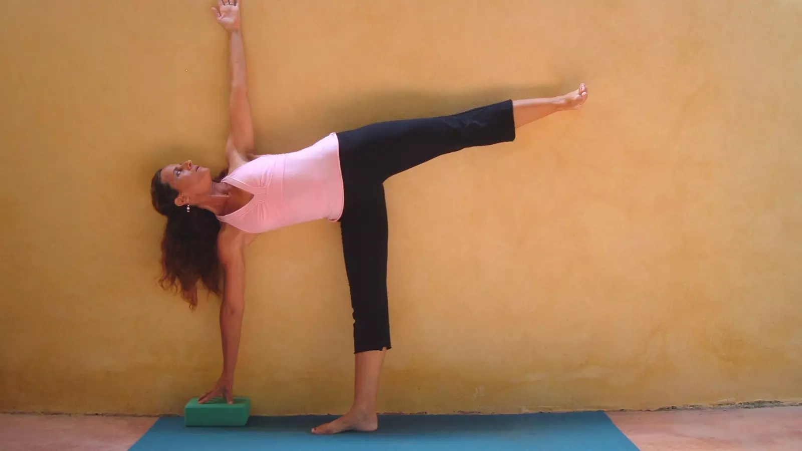 Image depicts a full version of Half Moon Pose (Ardha Chandrasana) at the Wall variation