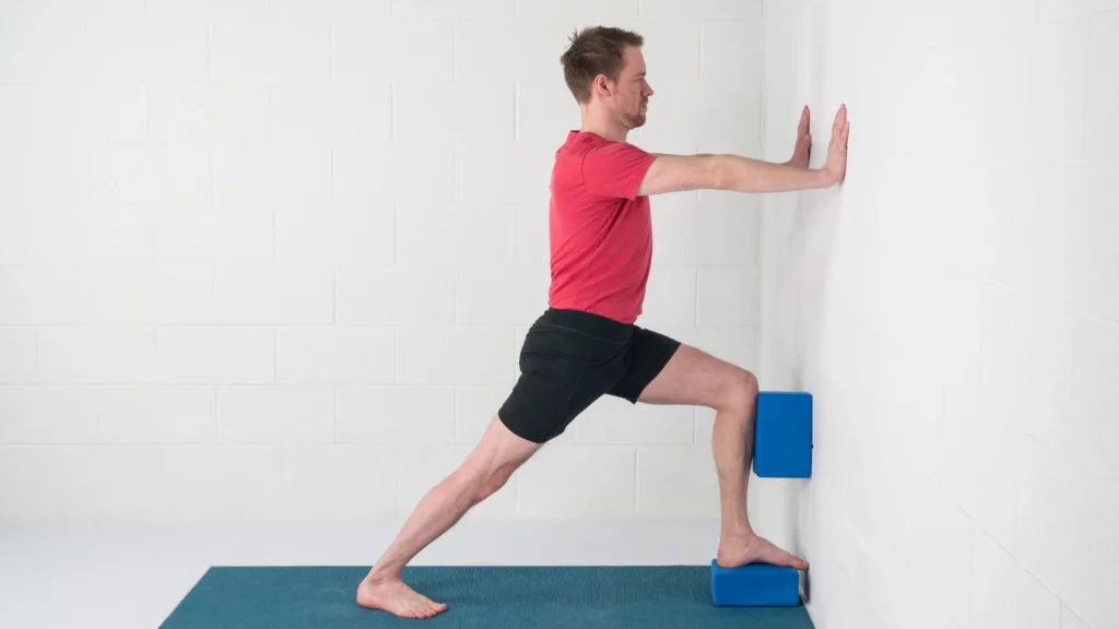 How to practice Yoga poses Crescent Lunge and Warrior 1 variations at the wall with yoga blocks for support. Pose variations like this support heart health.