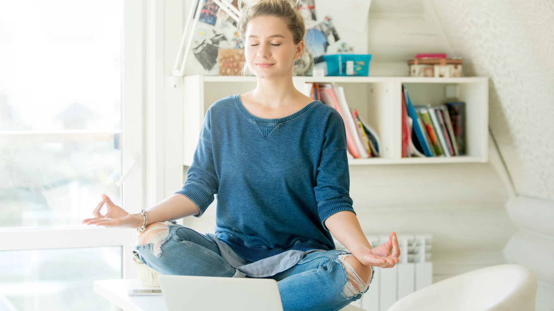 Portrait of an attractive woman on the working table. Lotus pose. Motivation concept and concept of taking care of yourself in order to take care of your work flow.