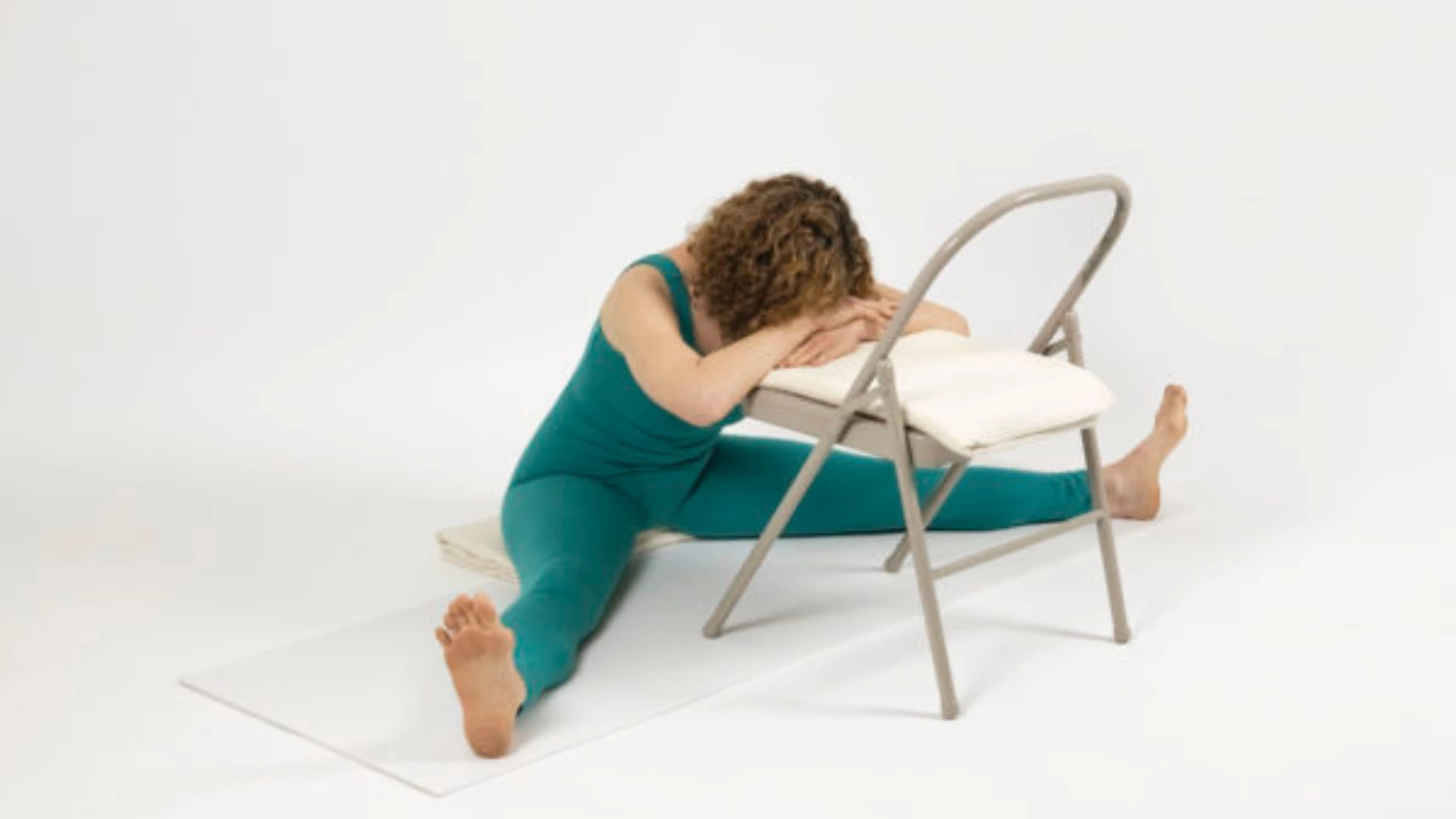 Image depicts a chair pose variation of Supported Wide Angle Forward Bend Pose.