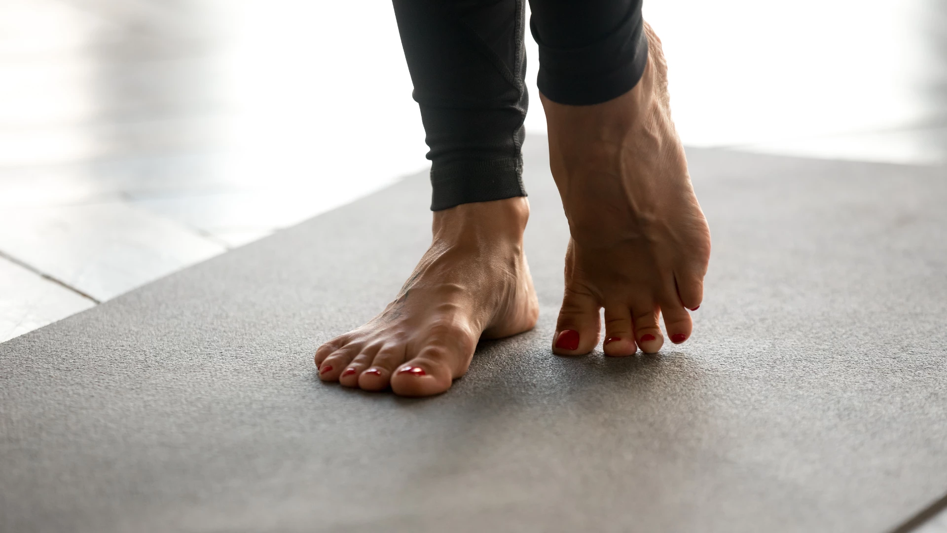 Sporty woman practicing yoga, doing exercises for stronger feet muscles, standing pose, working out and being barefoot.