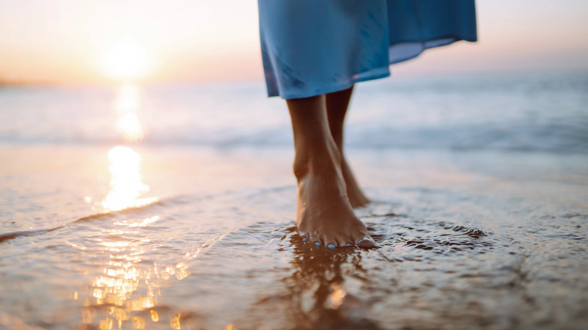 Walking barefoot in the sand and water for healthy feet and grounding connection to the earth.