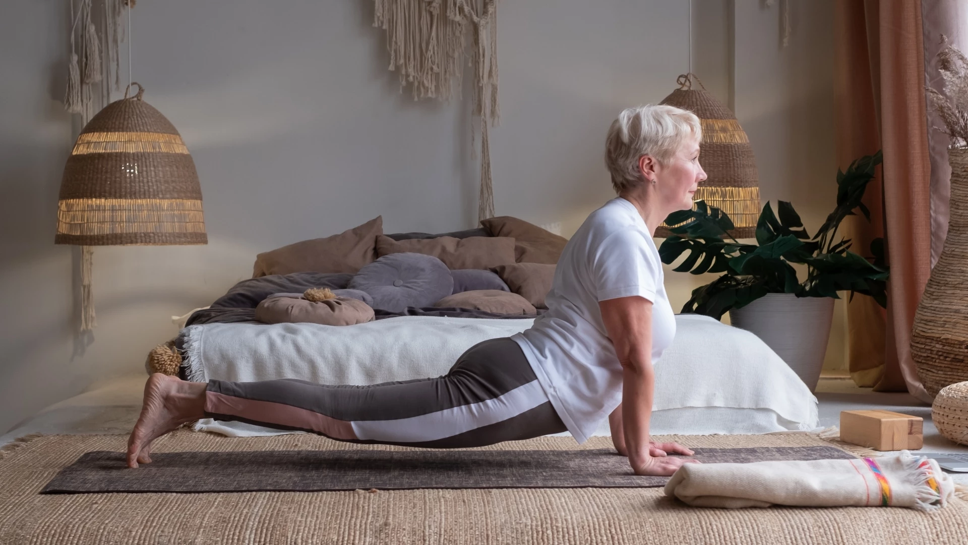  senior woman working out, prscticing Urdhva Mukha Svanasana or upward facing dog poase at home because yoga improves memory and overall health.