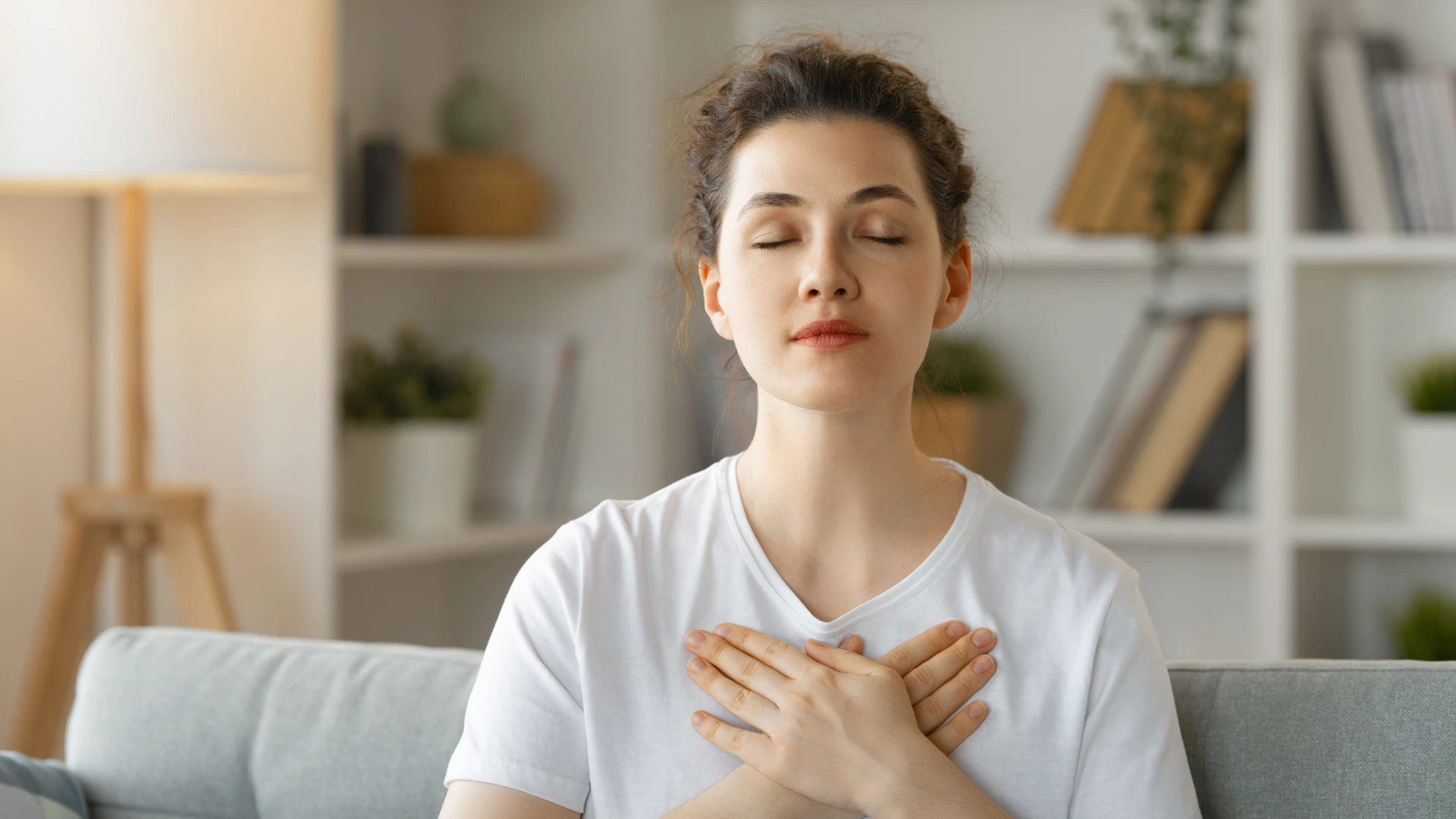 Calm beautiful young woman holding hands on her chest feeling grateful and thankful. Gratitude Mediation may be a beneficial yoga for major depresssive disprder.