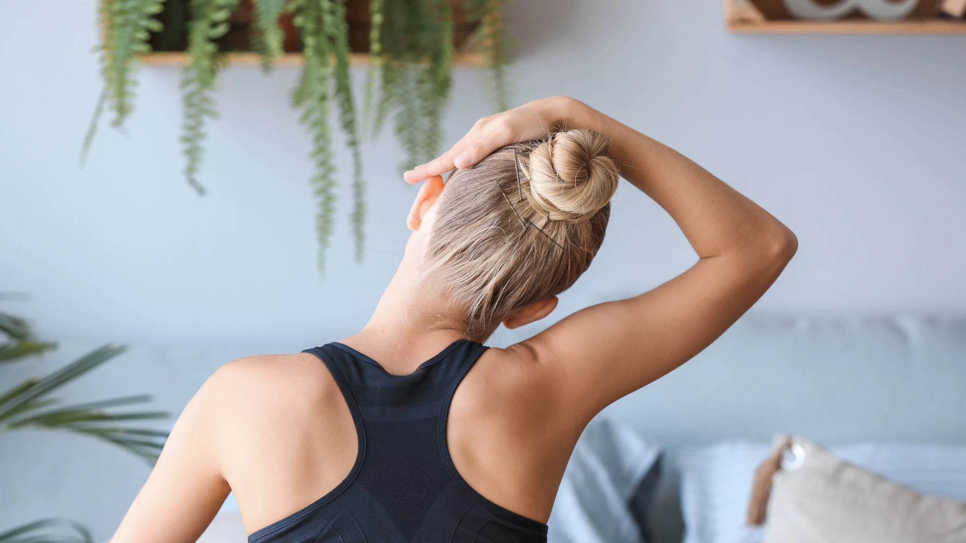 Young woman training at home, back view. Neck exercises can keep your neck healthy and avoid neck pain.