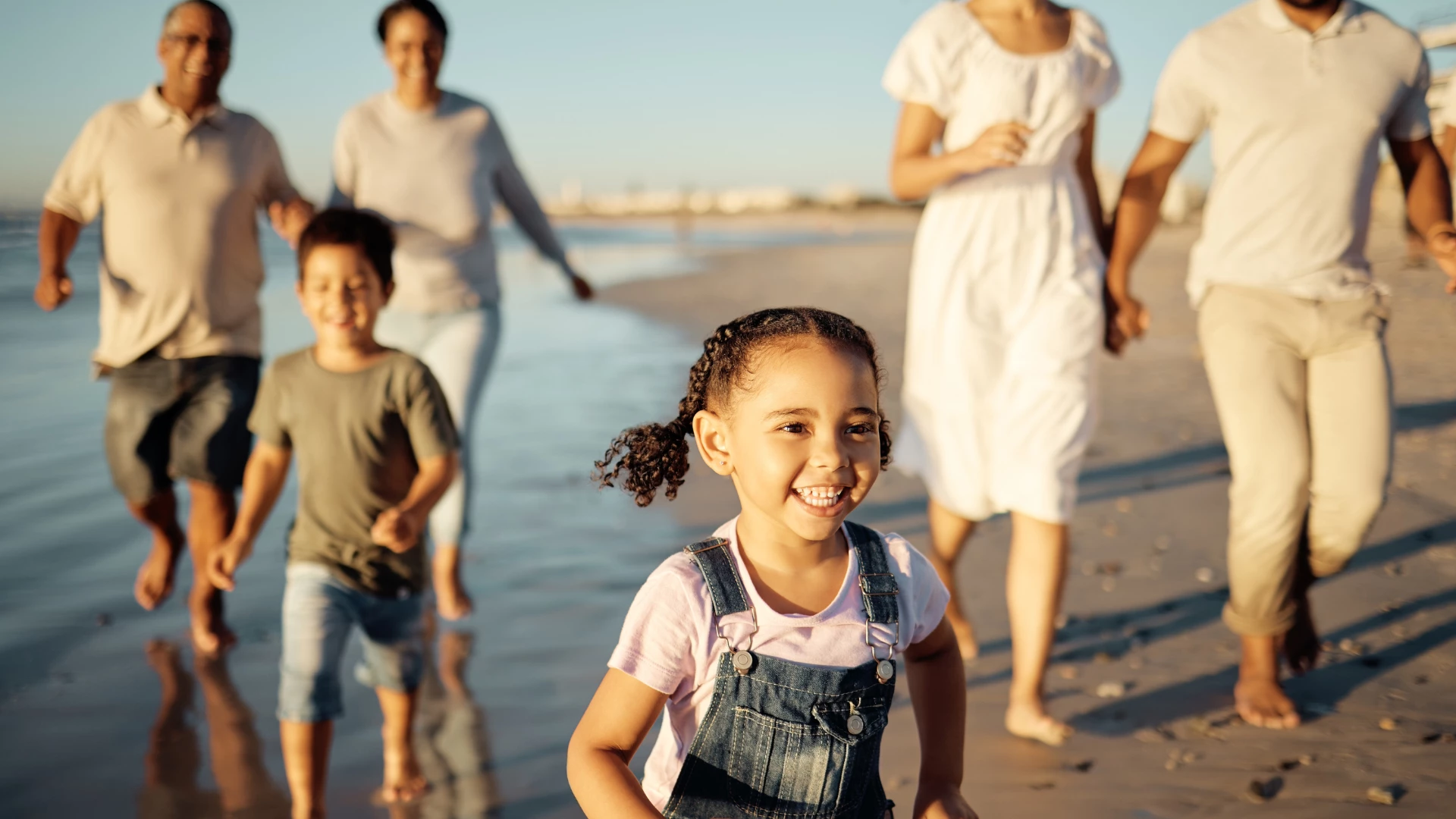 Family, girl and beach with children, Parents and grandparents walking together on holiday by the sea. Happy generations, concept of passing on family genetics and how genetics affects our overall health.