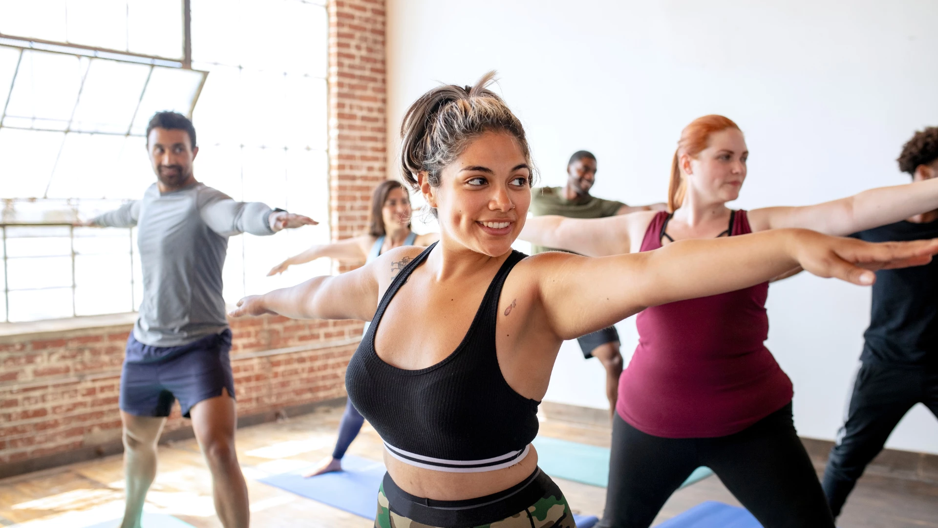 Diverse people practicing a Virabhadrasana ll yoga pose. Concept of yoga bodies need adequate protein plant or animal-based.