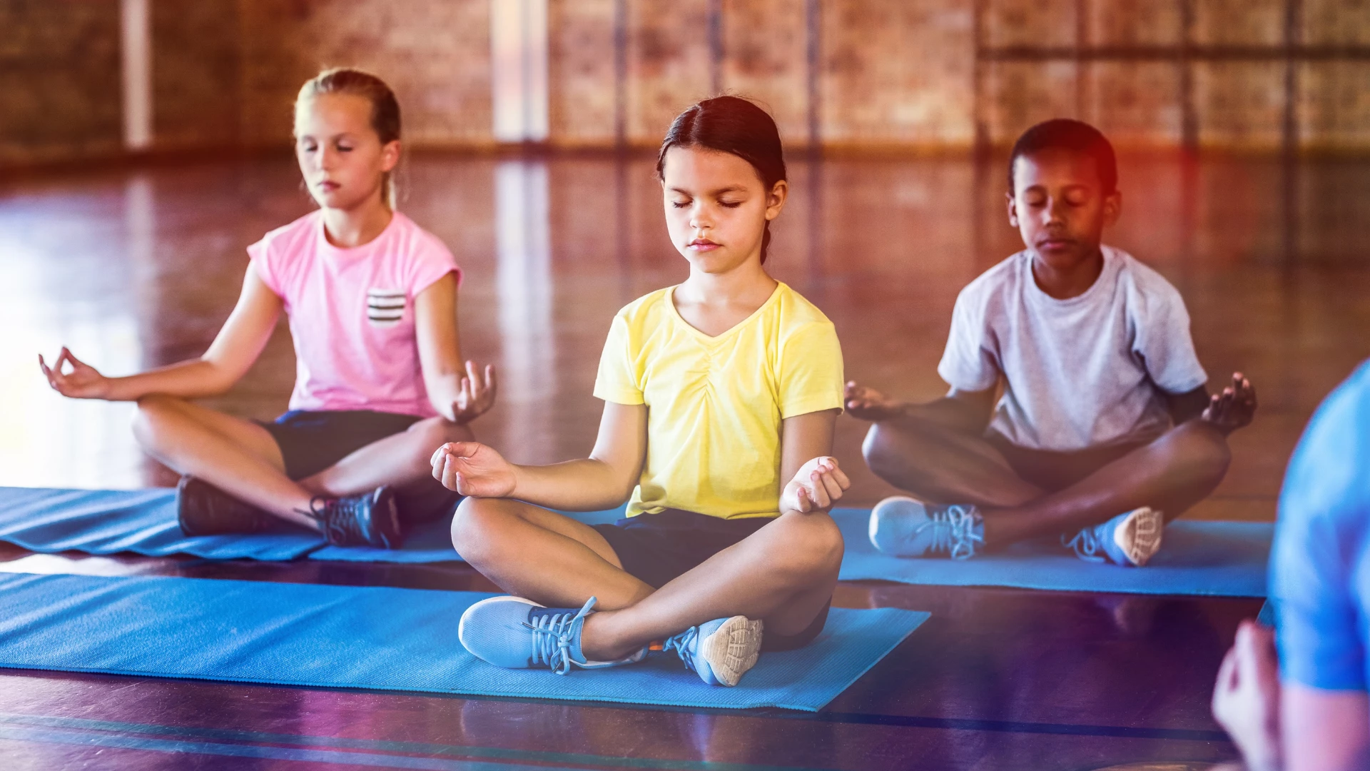 Benefits of yoga for kids is shown with kids sitting quietly in Easy Sitting Pose.