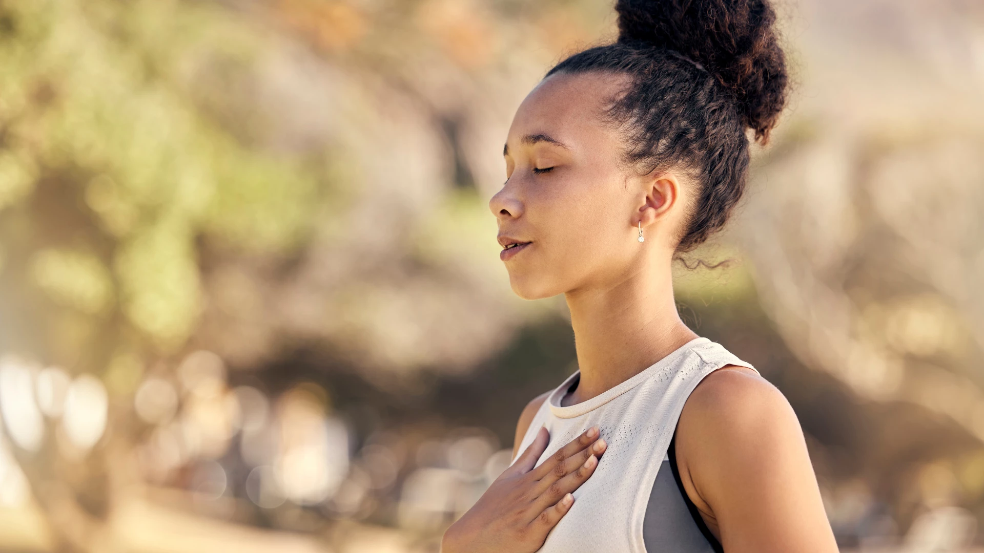 Black woman, breathing and with hand on her heart for meditation and wellness being peaceful and practicing gratitude.