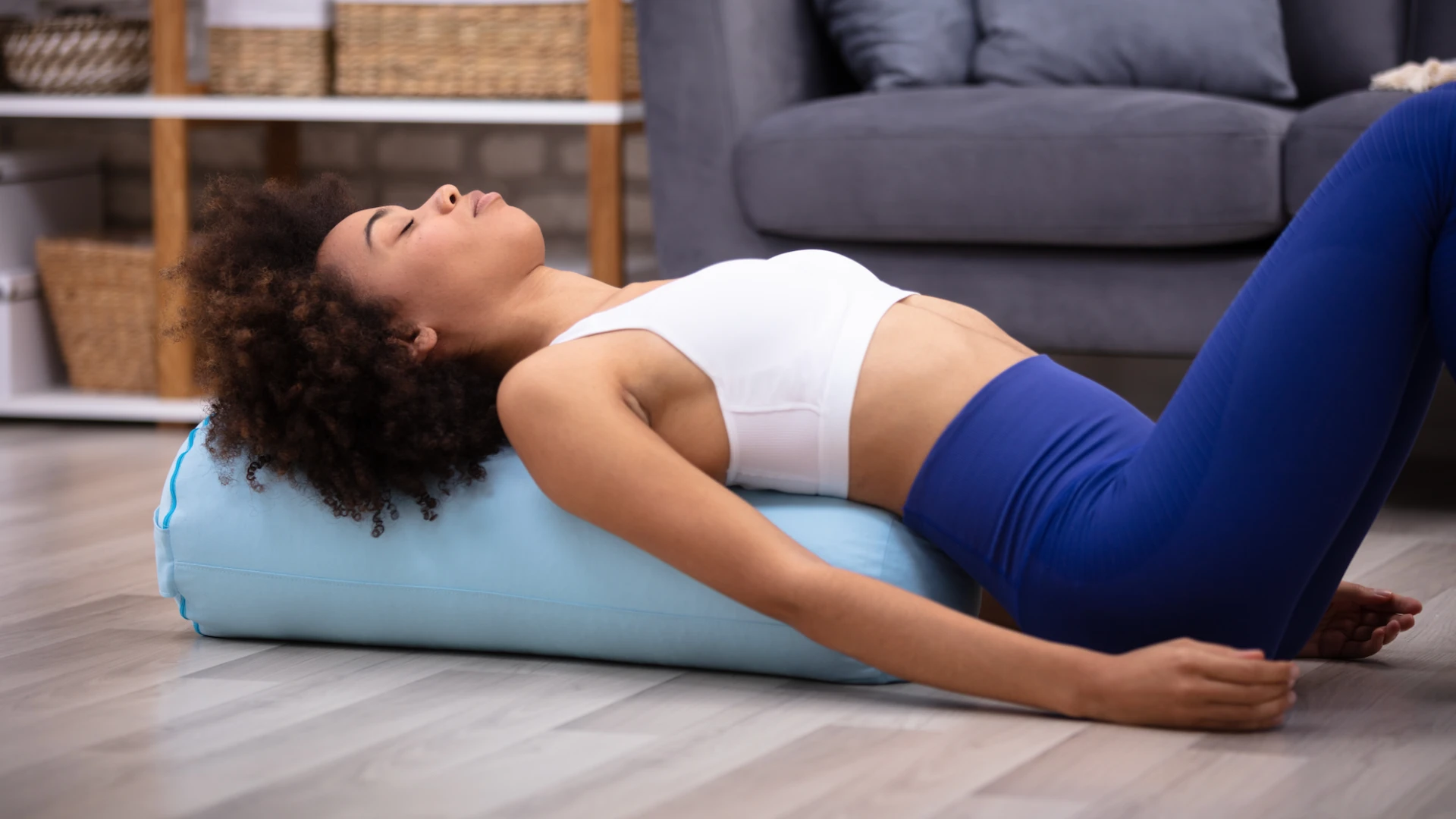 Woman practicing restorative heart opener with bolster to naturally evoke feelings of gratitude and openness